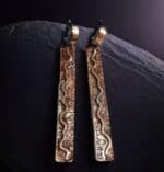 Серьги из меди с узором меандр, крупный план, золотистый оттенок, ручная работа.