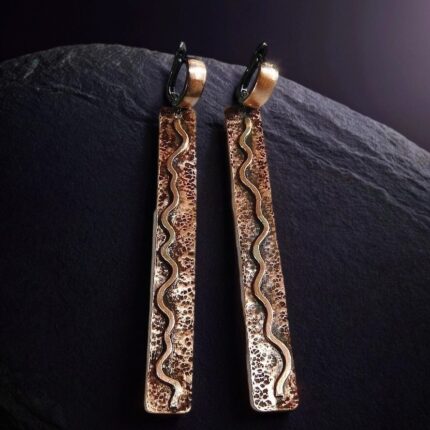Серьги из меди с узором меандр, крупный план, золотистый оттенок, ручная работа.