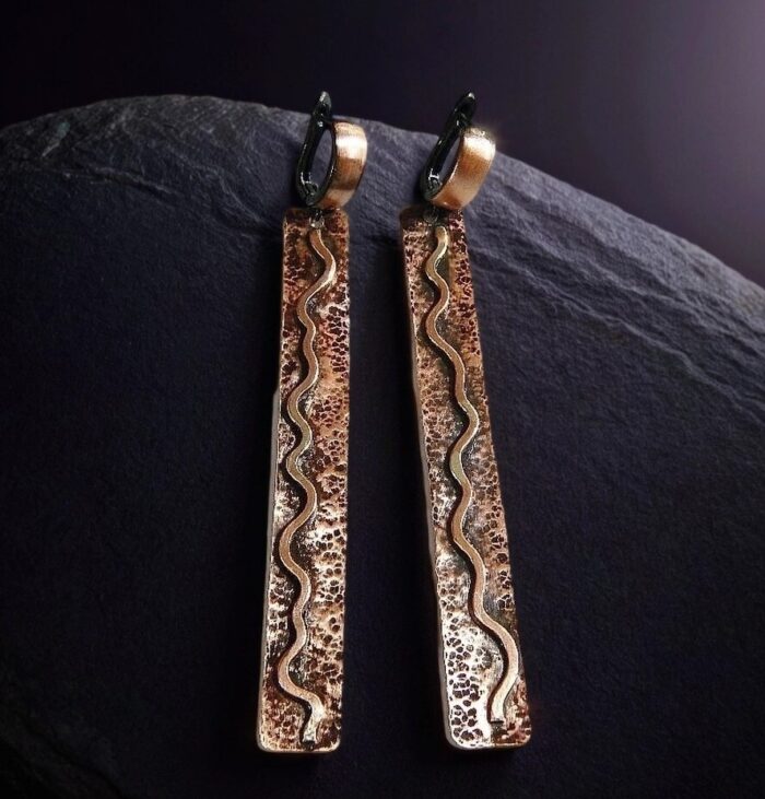 Серьги из меди с узором меандр, крупный план, золотистый оттенок, ручная работа.
